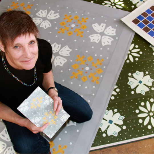 Margruite Krahn sitting with painted rugs